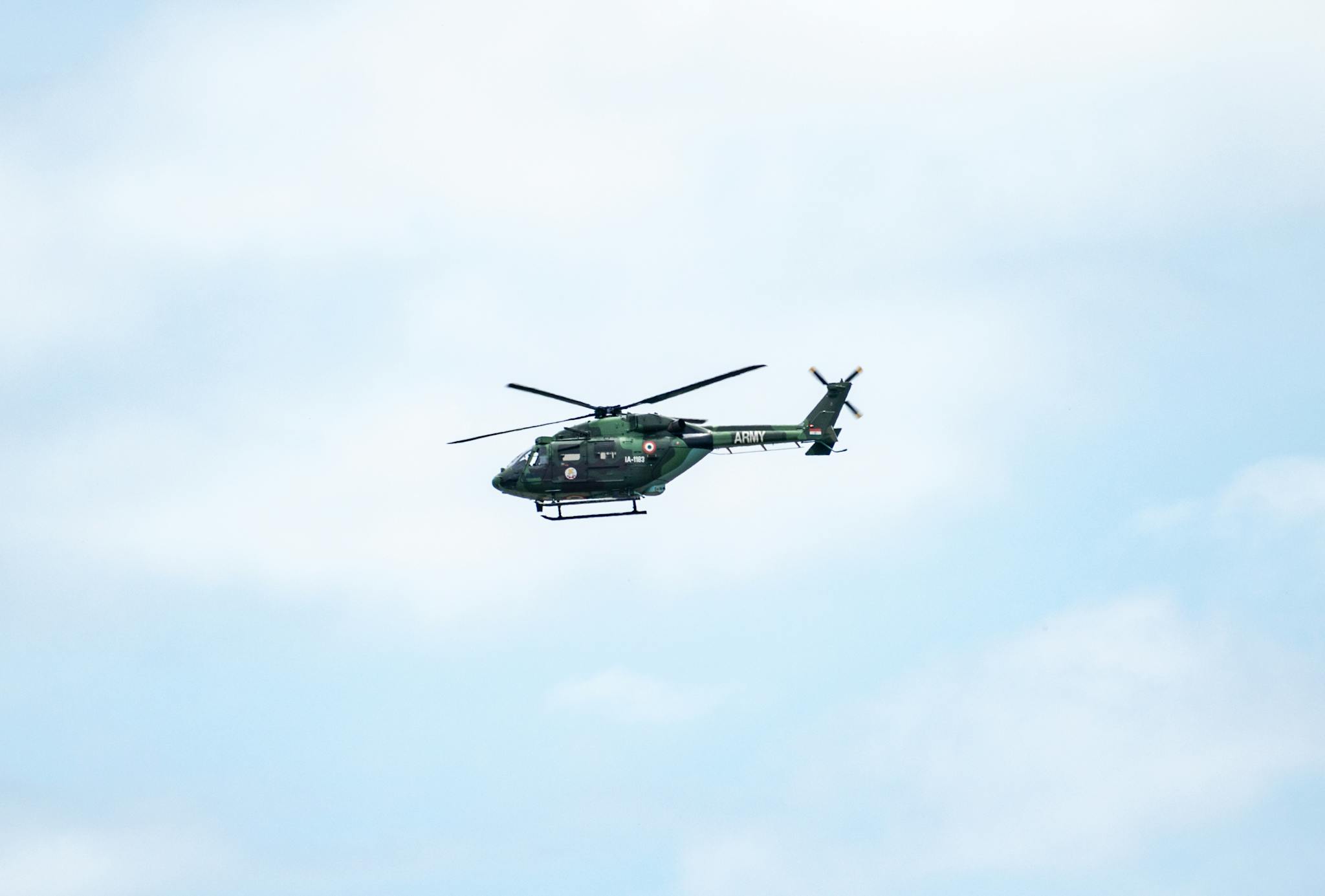 A military helicopter in flight against a bright blue sky, showcasing army aviation technology.
